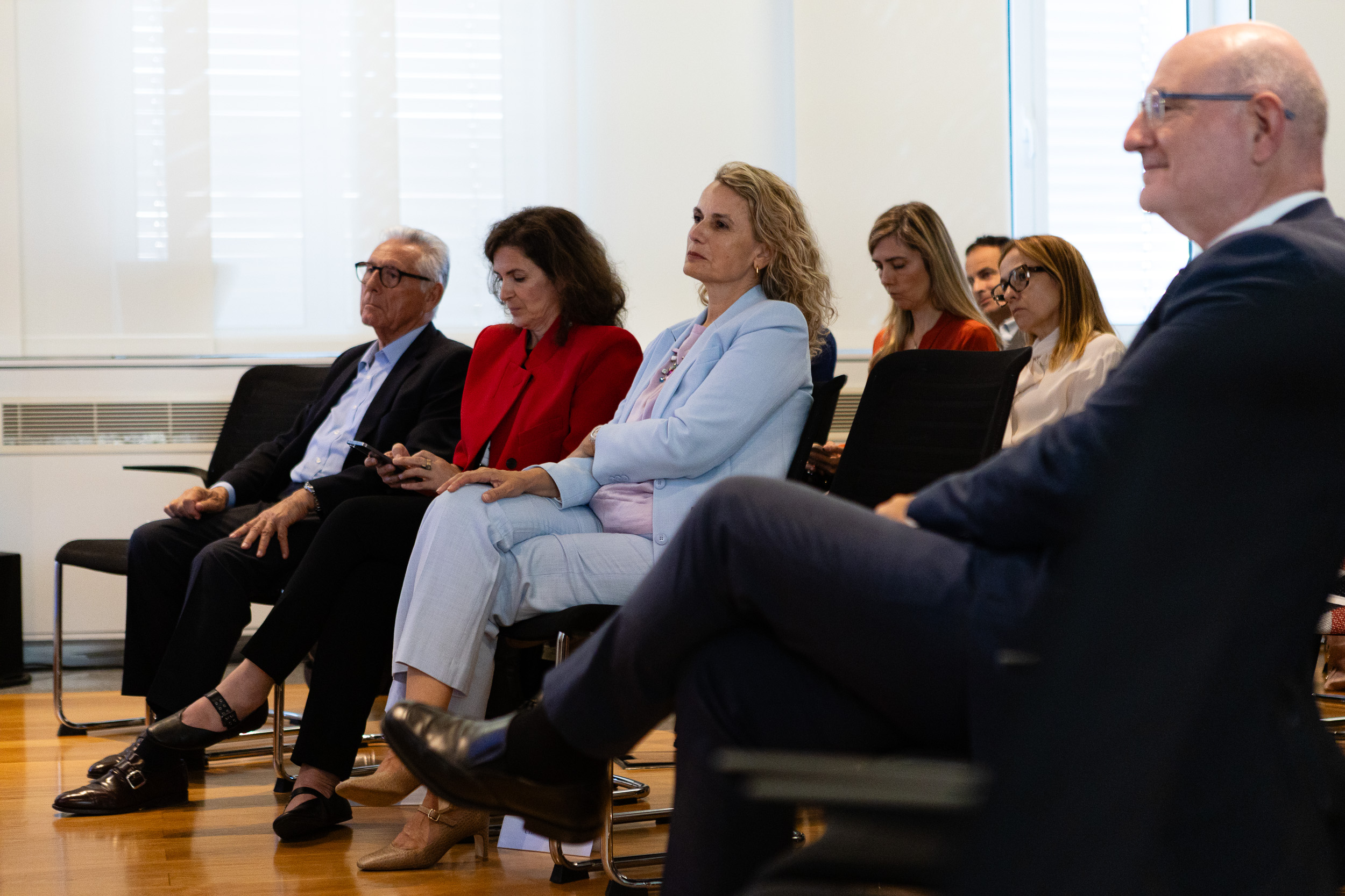 Group of professionals seated in a conference room, listening attentively during a meeting.